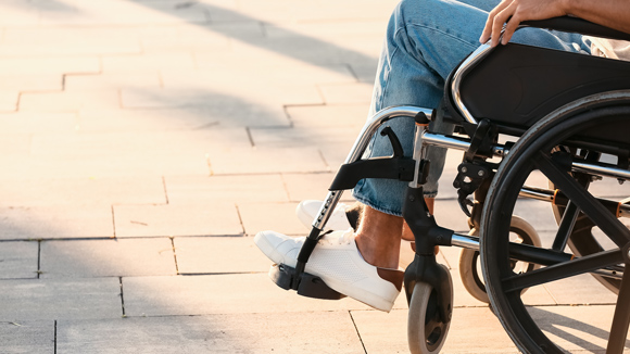 close up of person in wheelchair in jeans and white trainers